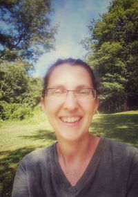 Portrait of smiling young woman wearing sunglasses against trees