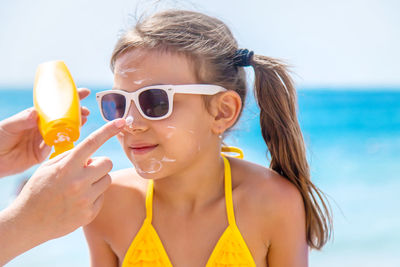 Mother applying suntan lotion on daughters face