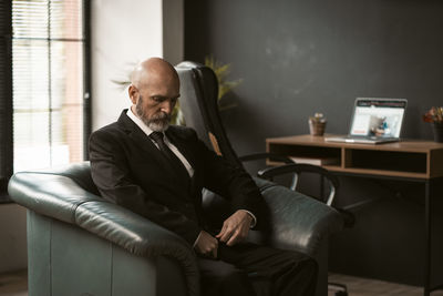 Side view of businessman using laptop while sitting on sofa at home
