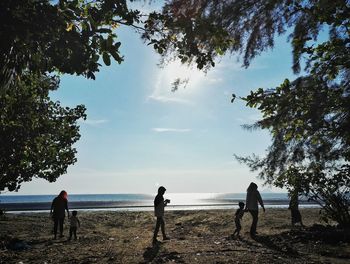 People at beach against sky during sunny day