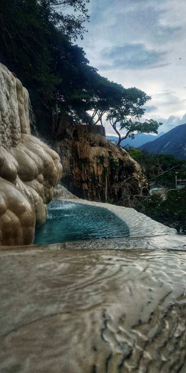 water, tree, sky, beauty in nature, mountain, cloud - sky, plant, nature, scenics - nature, rock, day, no people, tranquility, rock - object, tranquil scene, motion, solid, land, river, flowing water, outdoors, flowing