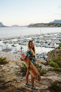 Young female with long board skate in front of moraira's yacht club