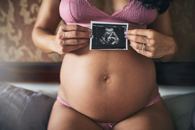 Midsection of pregnant woman holding book