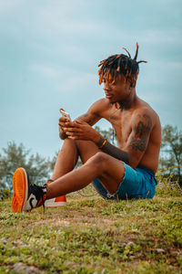 Full length of shirtless man sitting on field