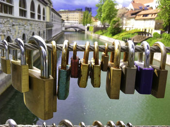 Close-up of padlocks hanging on railing against canal