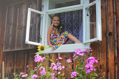 Happy laughing 5-6 years old girl opening a window in the house in village to meet a new day