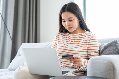 Happy woman making payment with credit card on laptop