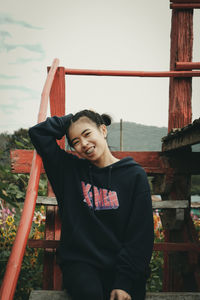 Portrait of smiling young woman standing against built structure