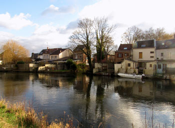 Buildings by river against sky