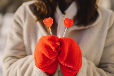 Valentines day card. woman in red mittens holding two heart shaped lollipops. i love you