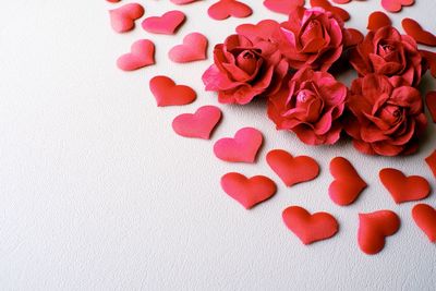 Close-up of heart shapes and artificial roses on white background