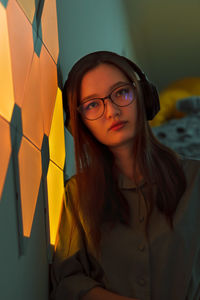 Brooding woman with headphones in yellow orange light listen to music, nightclub neon
