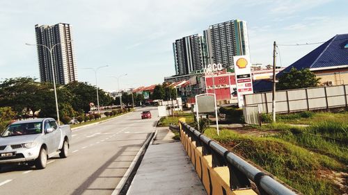 Road by buildings in city against sky