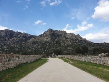 Road leading towards mountains against sky