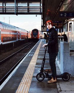 Side view of young man standing at railroad station