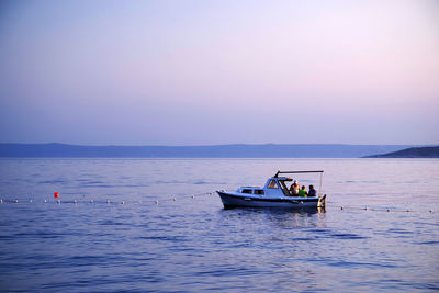 Boat sailing in sea against sky during sunset