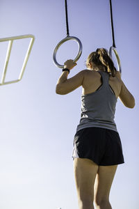 Low angle view of woman exercising against clear sky