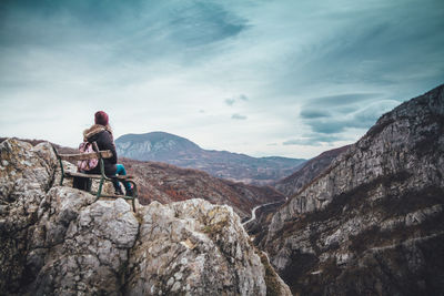 Man sitting on rock against mountains