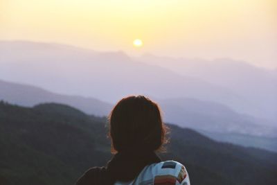 Rear view of woman on mountain against sky during sunset