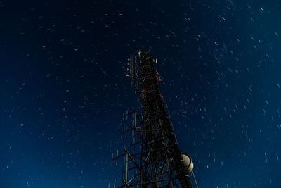 Low angle view of communications tower against sky at night