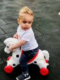 High angle view of cute baby boy sitting on rocking horse in city