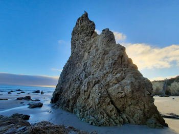 Rock formation on beach against sky