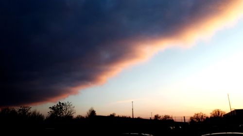 Low angle view of silhouette trees against dramatic sky