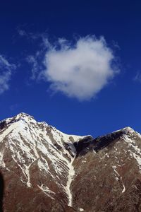 Low angle view of snowcapped mountains against blue sky