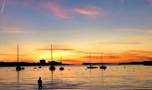 Silhouette sailboats in sea against sky during sunset