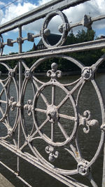 Low angle view of metal gate against sky