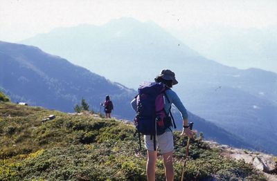 Rear view of people walking on mountain against sky