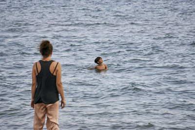 Rear view of men standing in sea