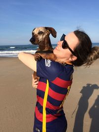 Woman with dog standing on sand at beach