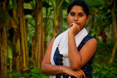 Portrait of beautiful young woman standing against plants