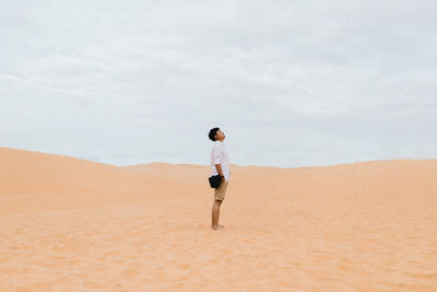 Side view of man standing on sand at desert