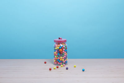 Gumball machine and gum balls spilling on a table.