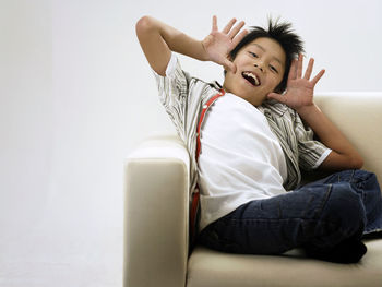 Portrait of smiling boy sitting against wall on sofa