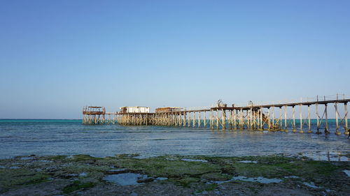 Pier over sea against clear blue sky