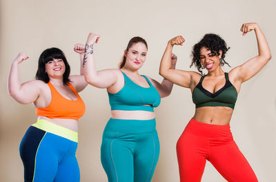 Happy friends flexing muscles standing against colored background