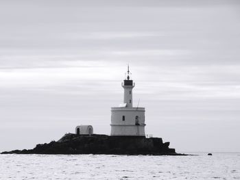 Lighthouse by sea against sky