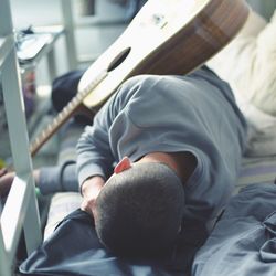 Sad guitarist lying on bed