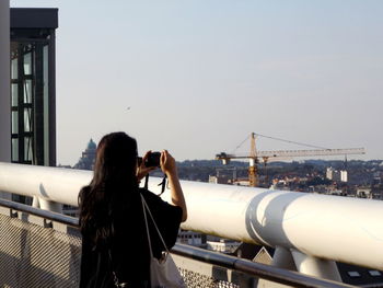 Woman photographing through smart phone against clear sky