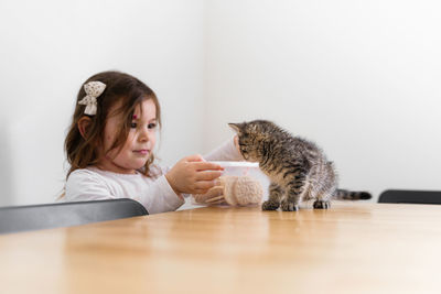 Portrait of girl with cat on table