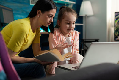 Women looking at camera while sitting in laptop