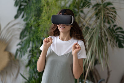 Emotional shocked woman in vr helmet using interactive technology for the first time at home garden