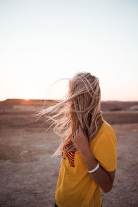 Rear view of woman standing on land against sky