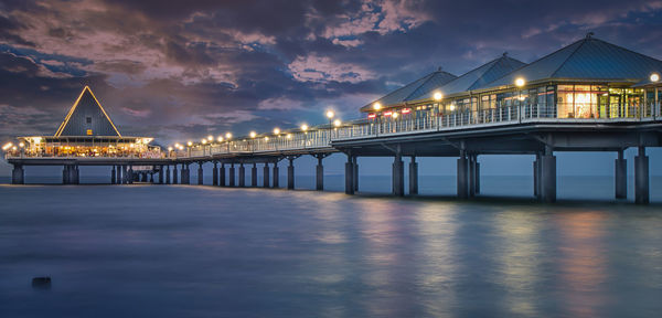 Illuminated bridge over sea against sky at night