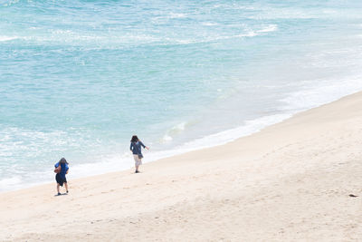 Full length of father and daughter walking on beach