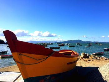 Boats moored on beach against blue sky