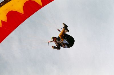 Low angle view of man paragliding against sky